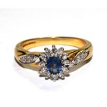 A sapphire and diamond cluster ring with diamond set shoulders, set in 18 carat yellow gold