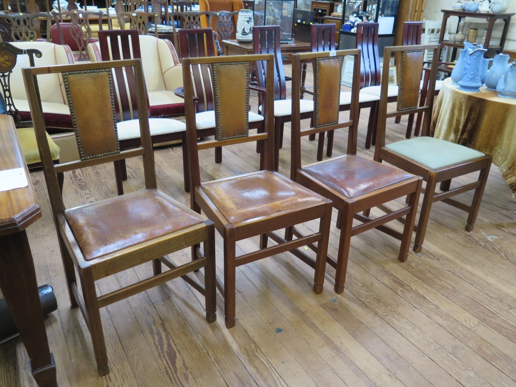 A set of four 1920s oak framed dining chairs, the top rails with exposed dovetails above leather