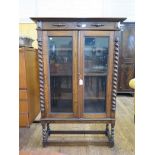 A 1930s oak display cabinet, with split barley twist decoration, twin glazed doors and barley