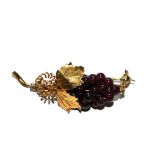 A gold bar brooch set with round garnets simulating a bunch of grapes