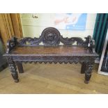 A Victorian Gothic style carved oak hall bench, with mask back, lunette frieze, and floral