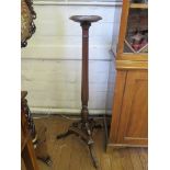 A 1920s mahogany torchere stand, with reeded baluster stem and scroll terminal on a triform base