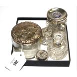 A collection of six toilet bottles with silver tops and a silver lidded pill box