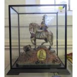 A polychrome figure of a Cromwellian soldier on horseback playing drums, the base with a plaque