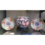 A Japanese porcelain Imari jardiniere, 21.5cm diameter x 16cm high, with carved hardwood stand and a