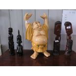 A ceramic figure of a Buddhist man, his hands aloft, 47 cm high and four African hardwood
