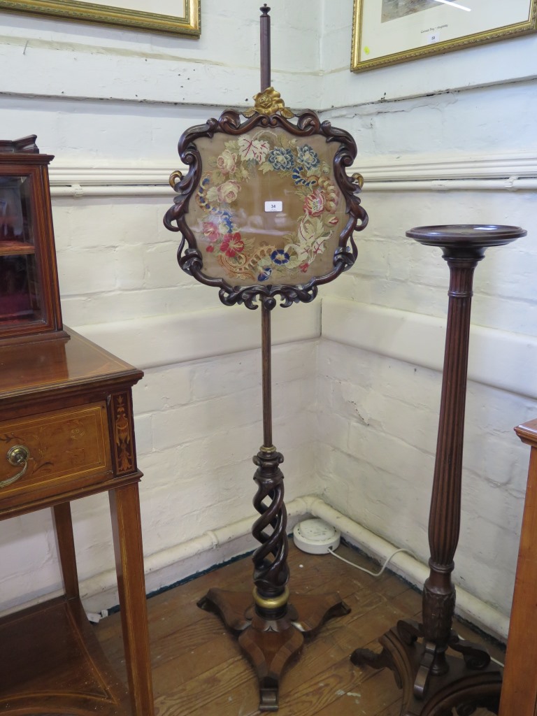 A mid Victorian rosewood pole screen, the foliate scroll screen with gilt rose motif enclosing a