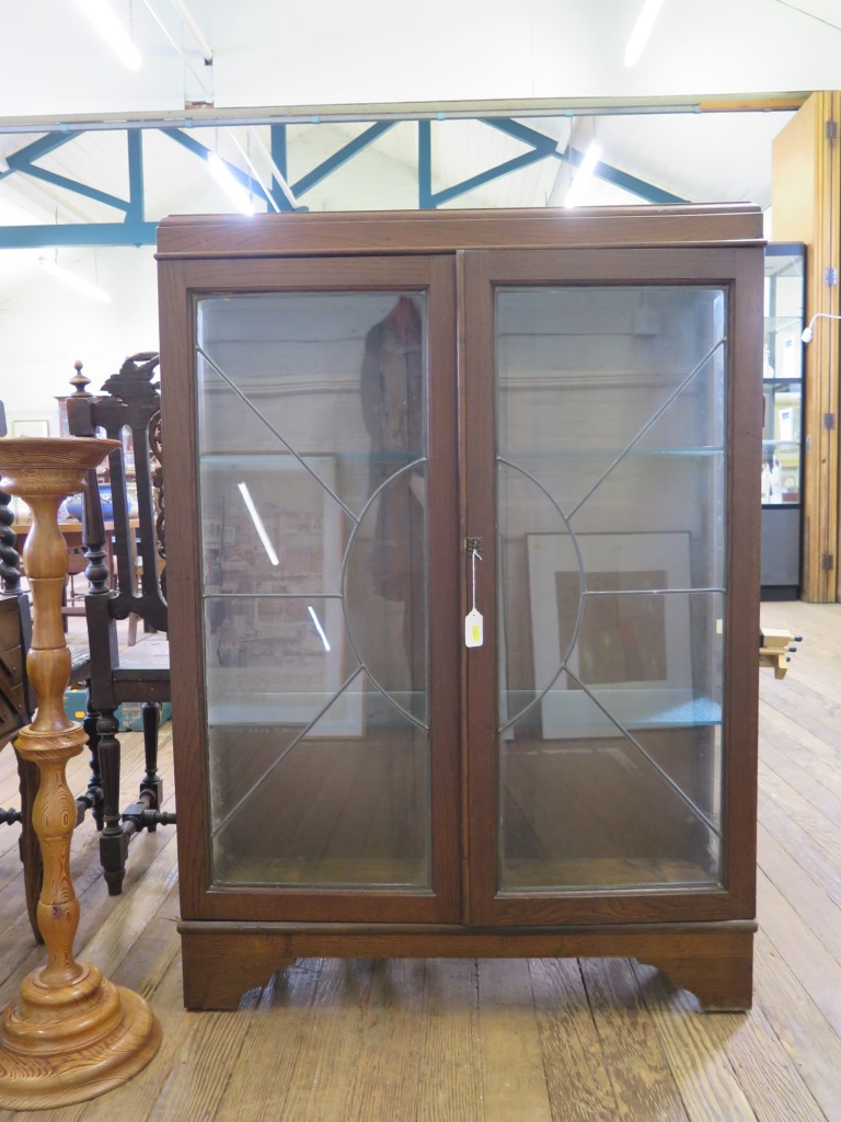 A 1930s oak display cabinet, with twin lead glazed doors on bracket feet, 91 cm wide