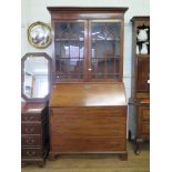 A George III mahogany bureau bookcase, with ogee arched glazed doors, over a sloping front enclosing