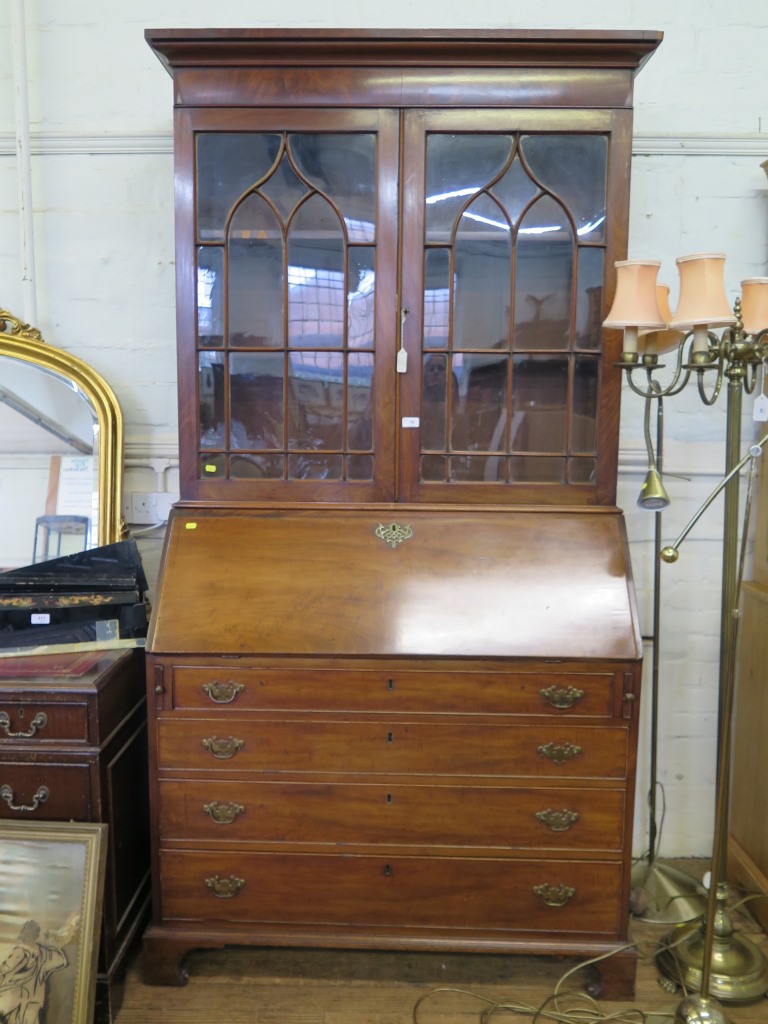 A George III mahogany bureau bookcase, with ogee arched glazed doors, over a sloping front enclosing