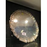 A Scottish silver salver, with pie crust edge and engraved with a crest, on three hoof feet,