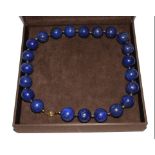 A single row necklace of large, uniform size, lapis lazuli beads in a case