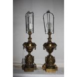 A pair of gilt metal urn form table lamps, with lion masks on fluted garland bases, possibly