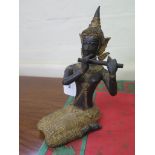 A Tibetan bronze figure of a seated flutist, 23 cm high
