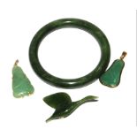 A collection of green stone items to include a bangle, two pendants and a carved bird brooch