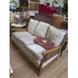 A 1930s walnut bergere settee, with cane back and double caned scroll arms, on acanthus carved