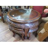 A Chinese carved hardwood nest of tables, the large circular table carved with figures and pagoda,