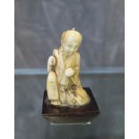 A miniature ivory carving of a Japanese man in contemplation, circa 1890-1910, carving 4 cm high
