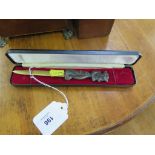 A brass letter opener with a caricature handle, in presentation case, 17 cm long