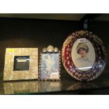 An oval glass photo frame with leaf decoration, 6" x 4" aperture, and two other photo frames