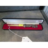 A brass letter opener with a caricature handle, in presentation case, 17 cm long