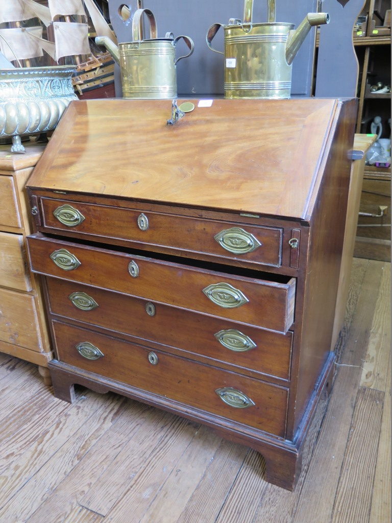 An early 19th century mahogany bureau, the sloping fall enclosing pigeon-holes and drawers, over