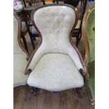 A Victorian walnut nursing chair with cream button upholstery, on cabriole legs and pot castors