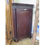 A George III style mahogany corner cabinet, the blind fret carved frieze over a panelled door and