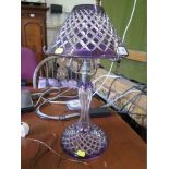 A purple overlay cut glass table lamp, the conical shade over a baluster form stem and circular