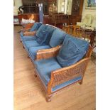 An Edwardian mahogany three piece double caned bergere suite, with rosette carved scroll arms,
