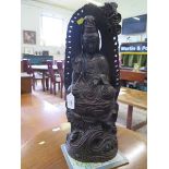 A carved hardwood figure of Quan-Yin, seated on a lotus flower with waves below, traces of
