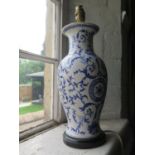A hand painted pottery lamp base with a blue trailing design