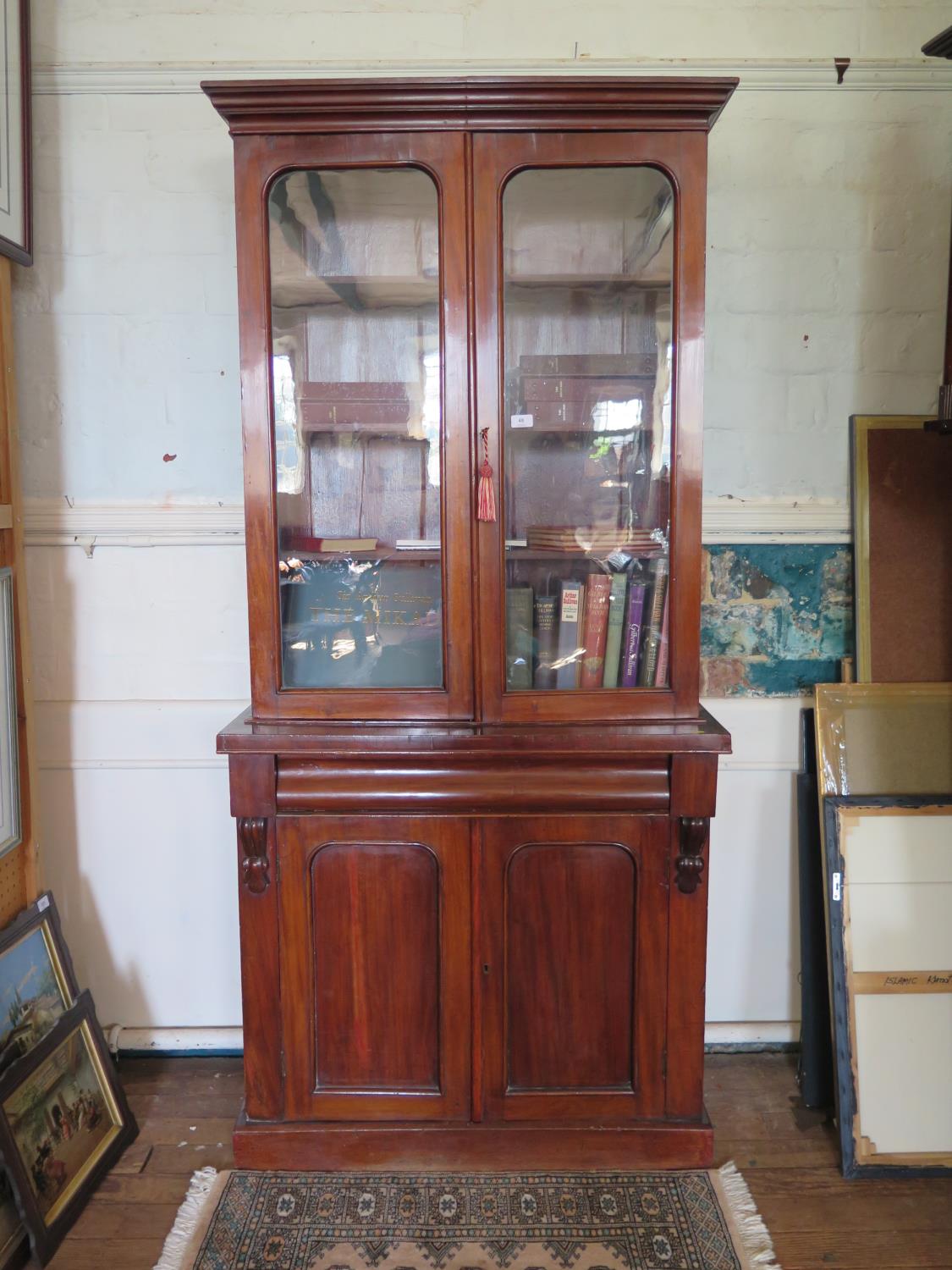 A mid Victorian mahogany bookcase cabinet, the twin glazed doors over a moulded frieze drawer