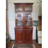 A mid Victorian mahogany bookcase cabinet, the twin glazed doors over a moulded frieze drawer