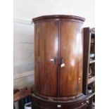 An early 19th century oak and mahogany bowfront corner cupboard, with three shelves, 99.5 cm high,