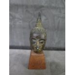 A miniature Buddha's head on wooden stand, 8.5 cm including stand