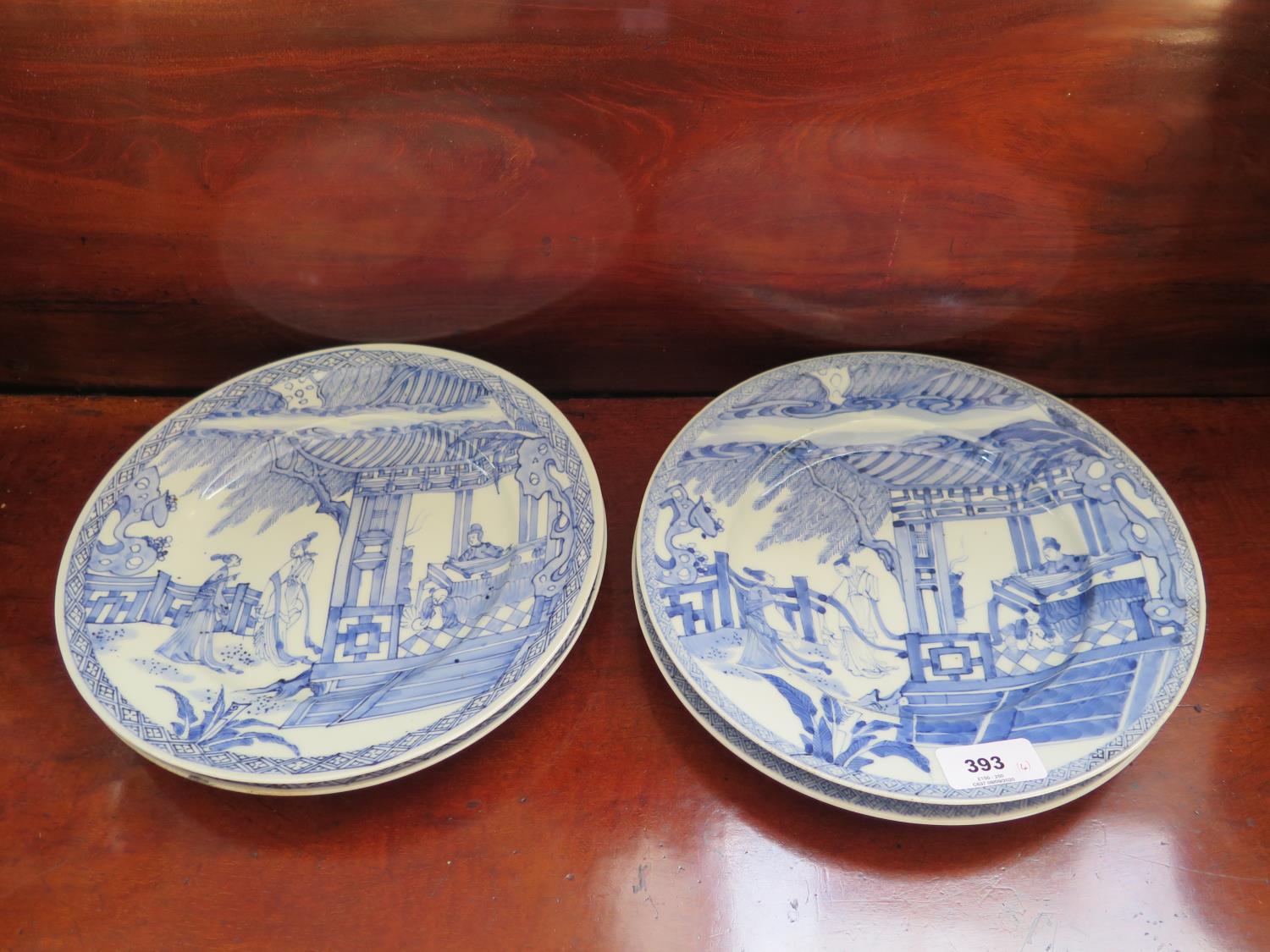 A set of four Chinese blue and white plates, each depicting figures in a room and gardens, 24.5 cm