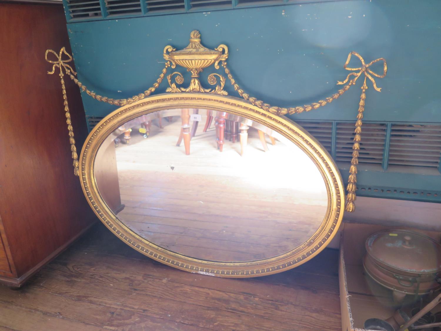 A George III style giltwood oval mirror, the bevelled plate within a tongue and dart frame