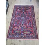 A modern Indian rug, with large floral design on a red field, with floral border, 130 x 75 cm