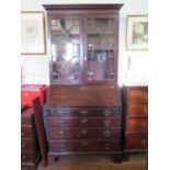 A George III mahogany bureau bookcase, the astragal glazed twin doors over a sloping fall above four