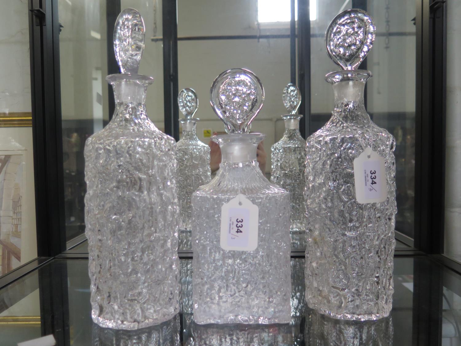 A pair of Whitefriars clear glass bark effect cylindrical decanters and stoppers, 34 cm high, and
