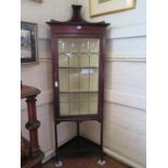 An Edwardian mahogany and boxwood lined corner cabinet, the raised back over a glazed door on square