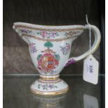 A Chinese export style jug, with entwined handle, enamelled floral sprays and coat of arms, 13 cm