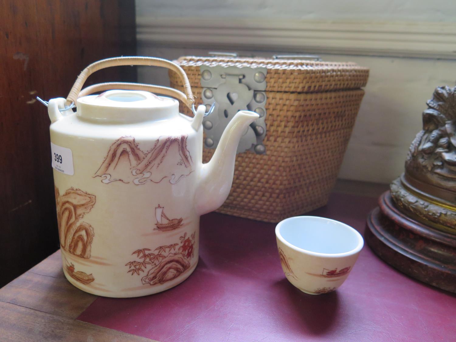 A Chinese teapot and two tea bowls, depicting figures and fishermen among islands, in a fitted