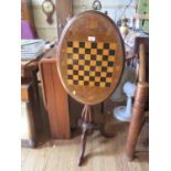 A Victorian inlaid walnut tripod games table, the oval top inlaid with a chequerboard and flowers on