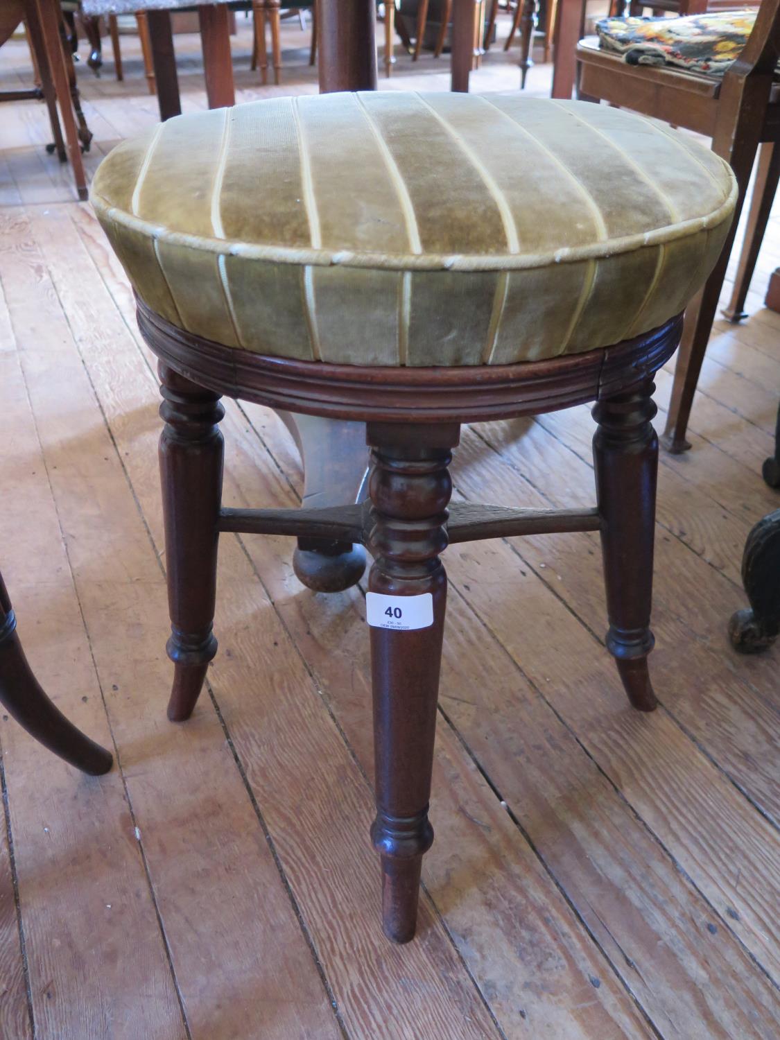 An early 19th century mahogany piano stool, the adjustable circular seat on turned outswept legs