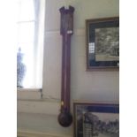 A George II style mahogany stick barometer, with broken pediment over a brass dial and globular