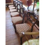 A set of six Victorian rosewood dining chairs, the scroll carved hoop backs above stuffover seats