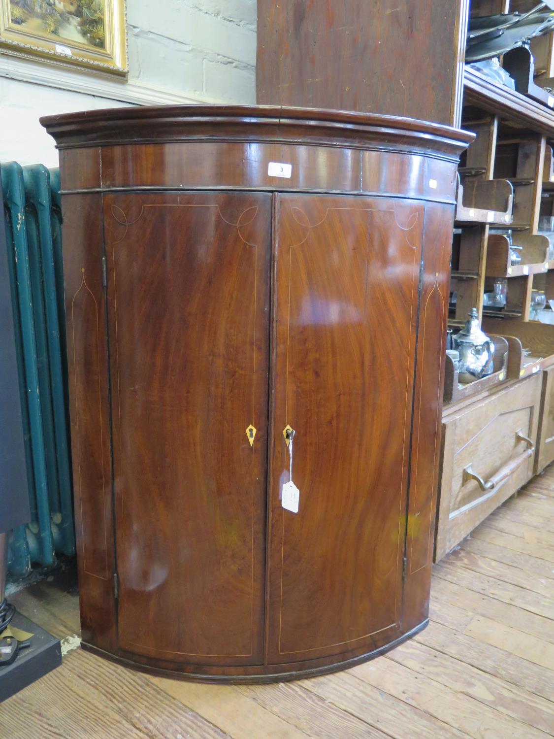 An early 19th century boxwood inlaid mahogany bowfront corner cupboard, with three shelves, 84 cm