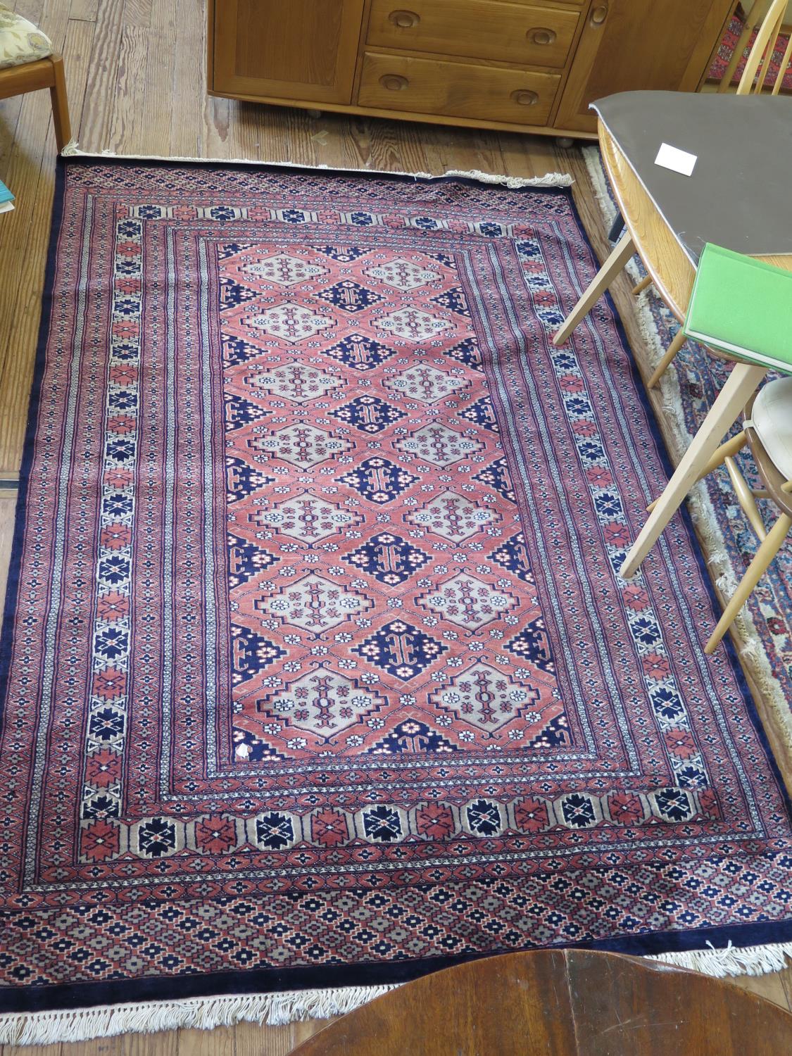 A Pakistani rug, the deep blue and grey medallions on a red field within a serrated multiple border,